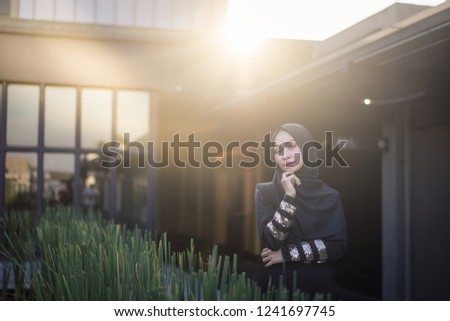 Portrait of a beautiful Asian woman wearing a hijab outdoors backlit by sun, shot with flares.  Muslim female hijab fashion portraiture concept.