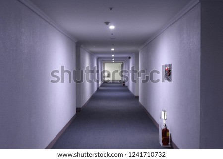 repeat of squares and subtle lighting in the long corridor. red fire extinguisher