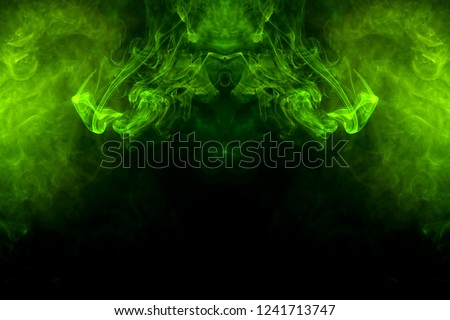 Fantasy print for clothes: t-shirts, sweatshirts.  Colorful green and yellow  smoke in the form of a skull, monster, dragon on a black isolated background. Background from the smoke of vape

