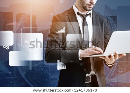 Unrecognizable businessman with laptop standing over cityscape background with business infographics interface and planet hologram foreground. Toned image double exposure