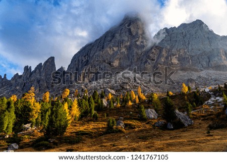 Colorful scenic view of majestic Dolomites mountains in Italian Alps. Majestic rocky mountains surrounded with yellow trees in autumn time.