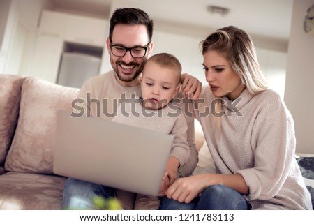 Happy family using a laptop on the sofa and watching cartoon.