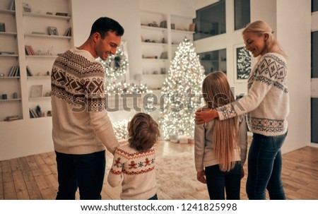 The happy parents with kids standing on the christmas tree background