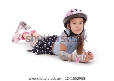 Happy little girl with roller skates and protective gear lying on the  floor - isolated on white background