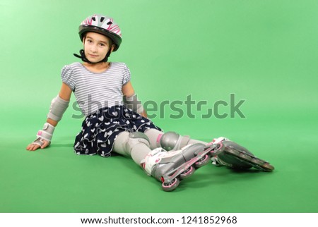 Pretty girl with rollerskates lying on green background