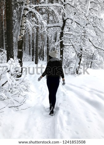Beautiful girl standing in the magnificent fairytale winter forest with trees covered with snow on the background and snowdrift all around