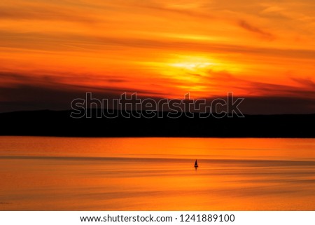 lonely small sailing ship in the red sunset the picture is held in black red