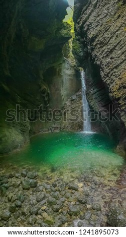 Waterfall in the forest at Kobarid Slovenia. Waterfall view from inside the cave. River with emerald green water flows through the crevasse
