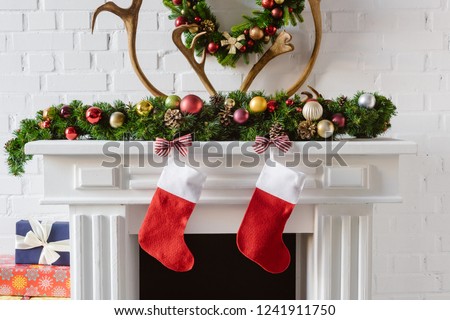 christmas wreath with decorations, stockings and deer horns over fireplace mantel