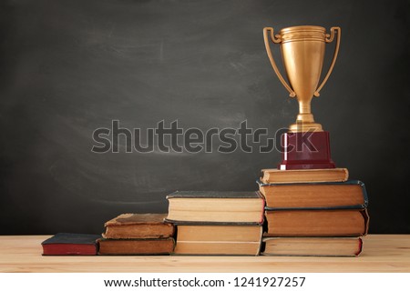 A concept image of education success, a stack of books arranged like a pyramid with golden trophy on top