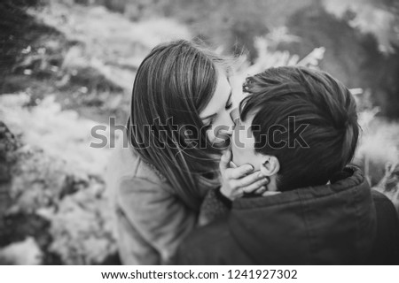 A romantic love couple walks in the snow park. Winter vacation. Man and woman hug and kiss, enjoying a stroll. Black and white photo.