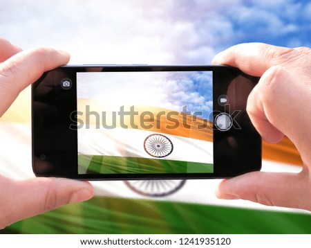 The hands of men make a phone photograph of the flag of India