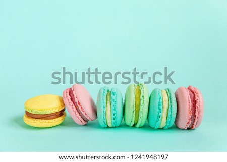 Sweet almond colorful pink blue yellow green macaron or macaroon dessert cake isolated on trendy blue pastel background. French sweet cookie. Minimal food bakery concept. Flat lay top view copy space