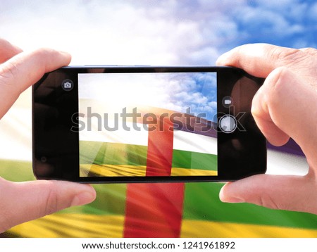 The hands of men make a phone photograph of the flag of Central African republic