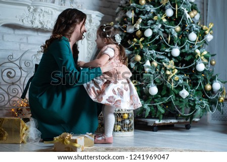 Merry Christmas and happy holidays. Mother and daughter having fun near the Christmas tree with gifts