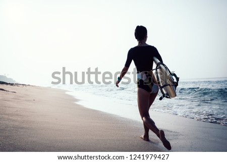 Surfer woman with surfboard walking on tropical beach