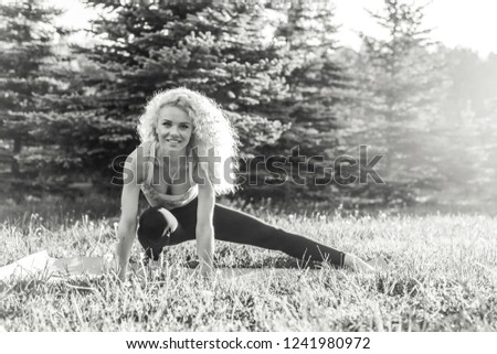 Image of young curly-haired sports woman practicing yoga on rug 