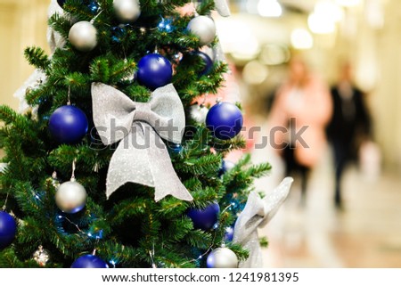 Image of decorated Christmas spruce with white and blue balls in store .