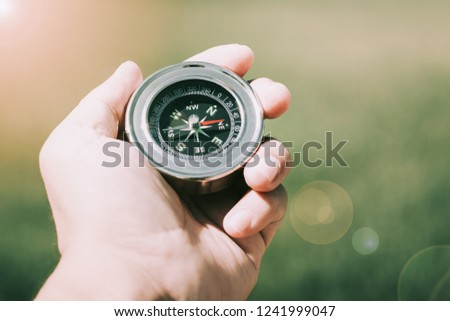 Hand holding compass and green nature background. Adventure. Alternative.