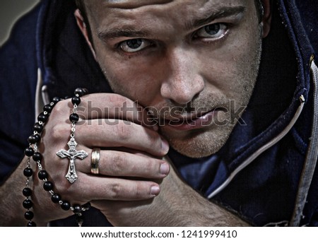 A thoughtful man with a rosary.A man who prays on the rosary. He has a piercing, thoughtful look.