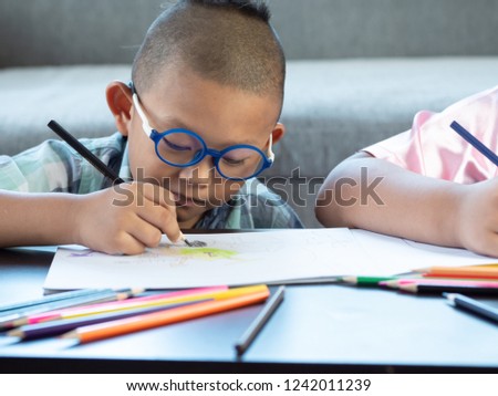Boy intend drawing a picture fun, enjoy drawing or write in book at home.