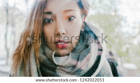 Asian girl looks with a scarf on the street