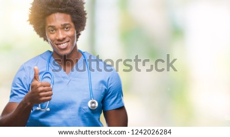Afro american surgeon doctor man over isolated background doing happy thumbs up gesture with hand. Approving expression looking at the camera with showing success.
