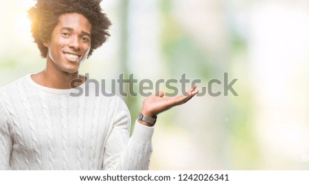 Afro american man over isolated background smiling cheerful presenting and pointing with palm of hand looking at the camera.