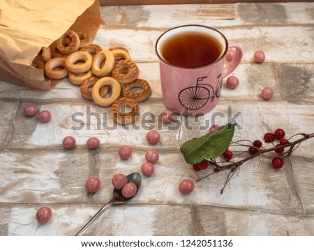 Light lunch of bagels scattered on the table, a sprig of wild apple trees, tea with a teaspoon