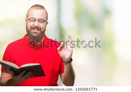 Young hipster man wearing glasses and reading a book over isolated background doing ok sign with fingers, excellent symbol