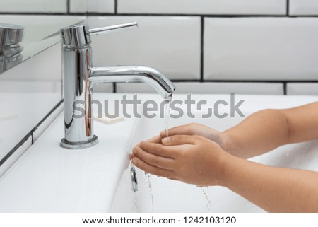 Kid washing hands in a white basin with a bar of white soap