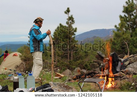 A tourist makes a fire on the slope of the mountain "Kosvinsky stone" for cooking dinner. An experienced and brutal tourist in the mountains of the Urals, Russia