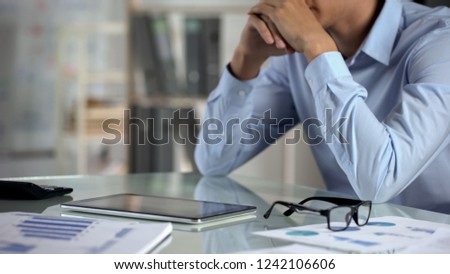 Pensive businessman using tablet, counting calculator, small business income Royalty-Free Stock Photo #1242106606