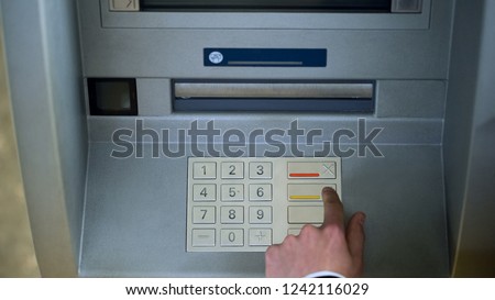 Man correcting pin code on ATM keyboard, transfer funds between bank accounts