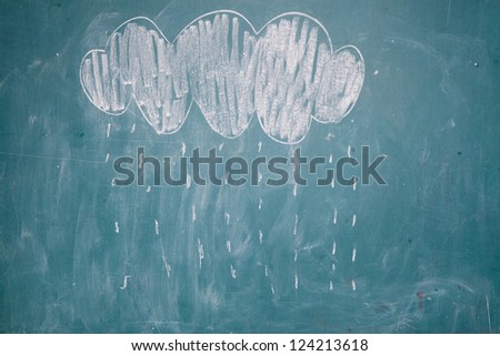 Chalk drawing by young child on chalkboard of rain cloud with raindrops falling