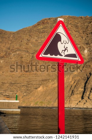 Waves warning sign with cliff background