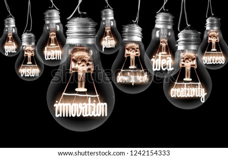Photo of light bulbs with shining fibres in a shape of INNOVATION, concept related words isolated on black background