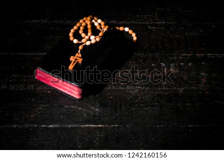 A bright book with a rosary on dark boards