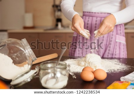 Unrecognizable young woman sprinkling flower over pasta or pizza dough