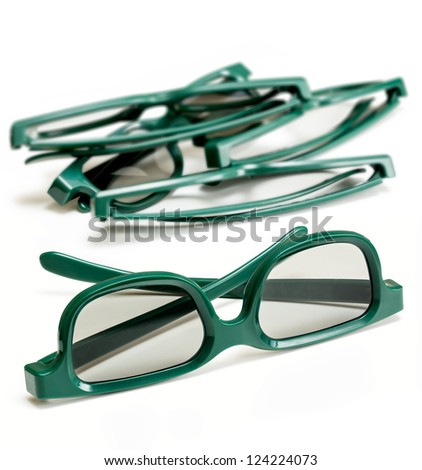Pair of green 3d polarized glasses for watching 3-d movies in cinema isolated against white with stack of used specs in background