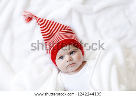 Cute adorable baby child with Christmas winter cap on white background. Happy baby girl or boy smiling and looking at the camera. Close-up for xmas holiday and family concept