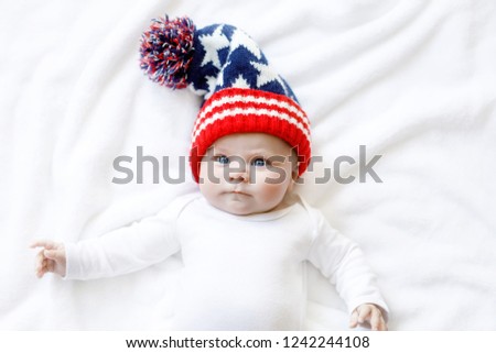 Cute adorable baby child with Christmas winter cap on white background. Happy baby girl or boy smiling and looking at the camera. Close-up for xmas holiday and family concept