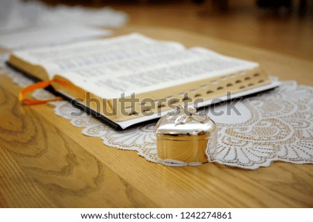 A silver box for wedding rings in the form of a heart is on the table next to the open Bible. Copy space
