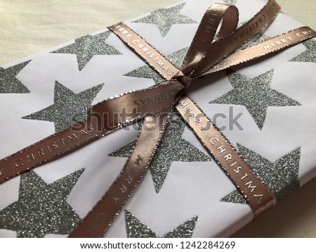Beautifully wrapped Christmas present decorated with a ribbon tied in a bow on a plain background