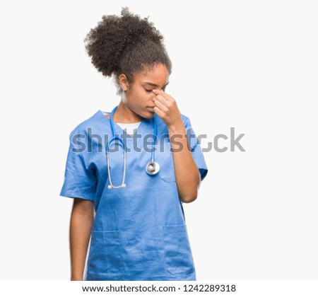 Young afro american doctor woman over isolated background tired rubbing nose and eyes feeling fatigue and headache. Stress and frustration concept.