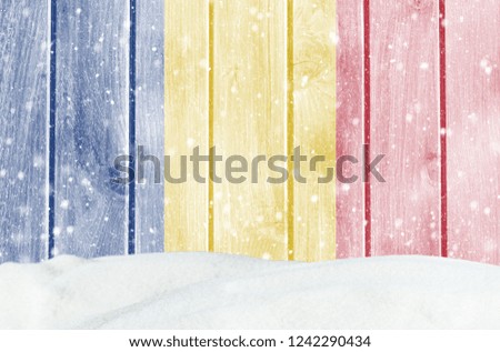 Christmas winter background with wooden wall, falling snow, snowdrift and Romanian flag