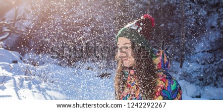Happy winter fun woman throwing snow banner. Panorama crop of outdoor lifestyle girl playing in snow outside laughing in yellow coat, hat, gloves and scarf.