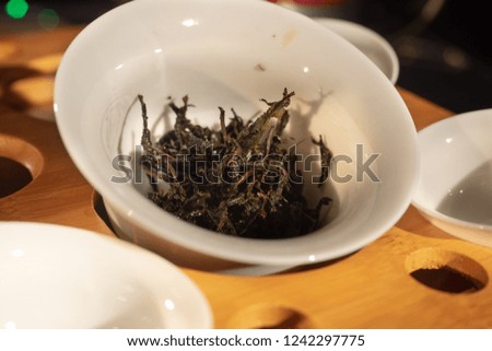 Chineese tea ceremony with tea leaves and white cups at wooden tea table
