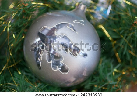 Macro picture of the ceramic Christmas decoration (silver ball with a bird) on the branch of Christmas tree. New year/Christmas background