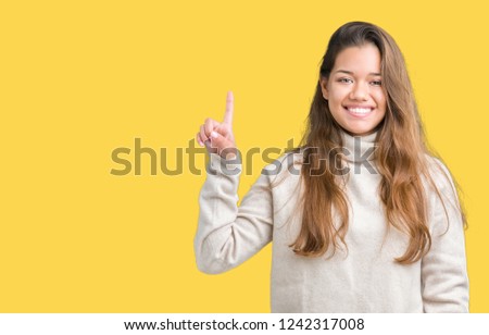 Young beautiful brunette woman wearing turtleneck sweater over isolated background showing and pointing up with finger number one while smiling confident and happy.